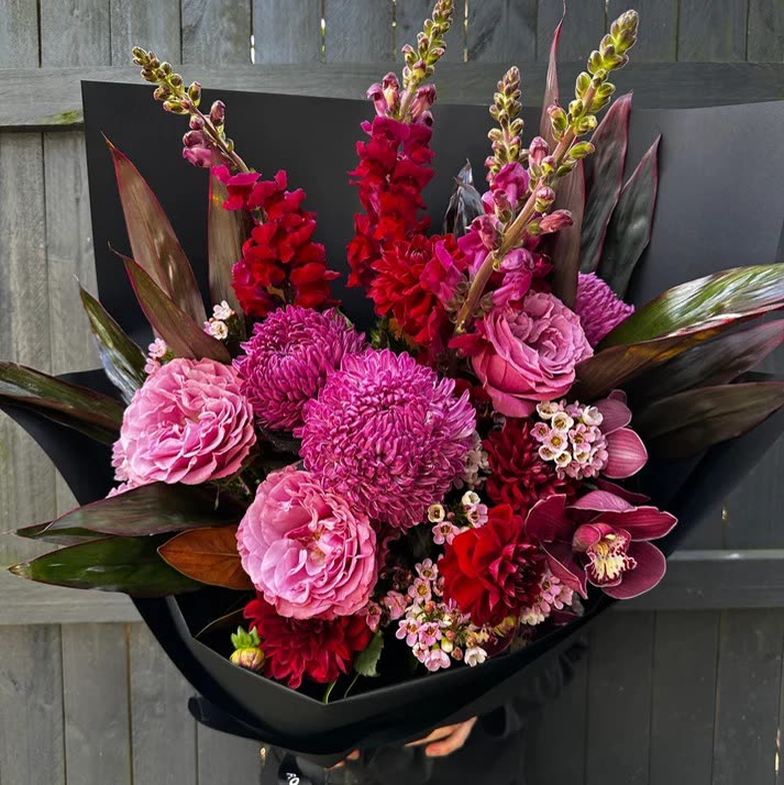 Current ad: pink and magenta bouquet in black wrap against a fence