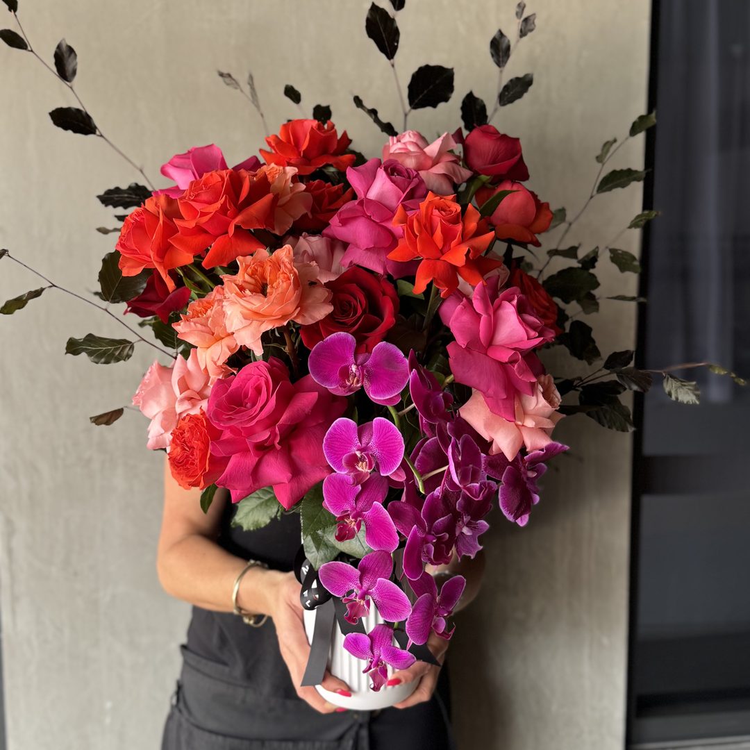Red roses and magenta orchids held in both arms
